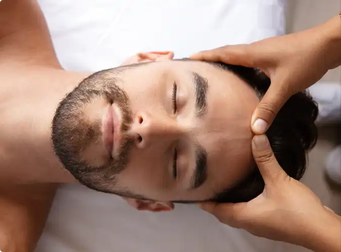 Person receiving forehead massage with loving hands for relaxation and stress relief.