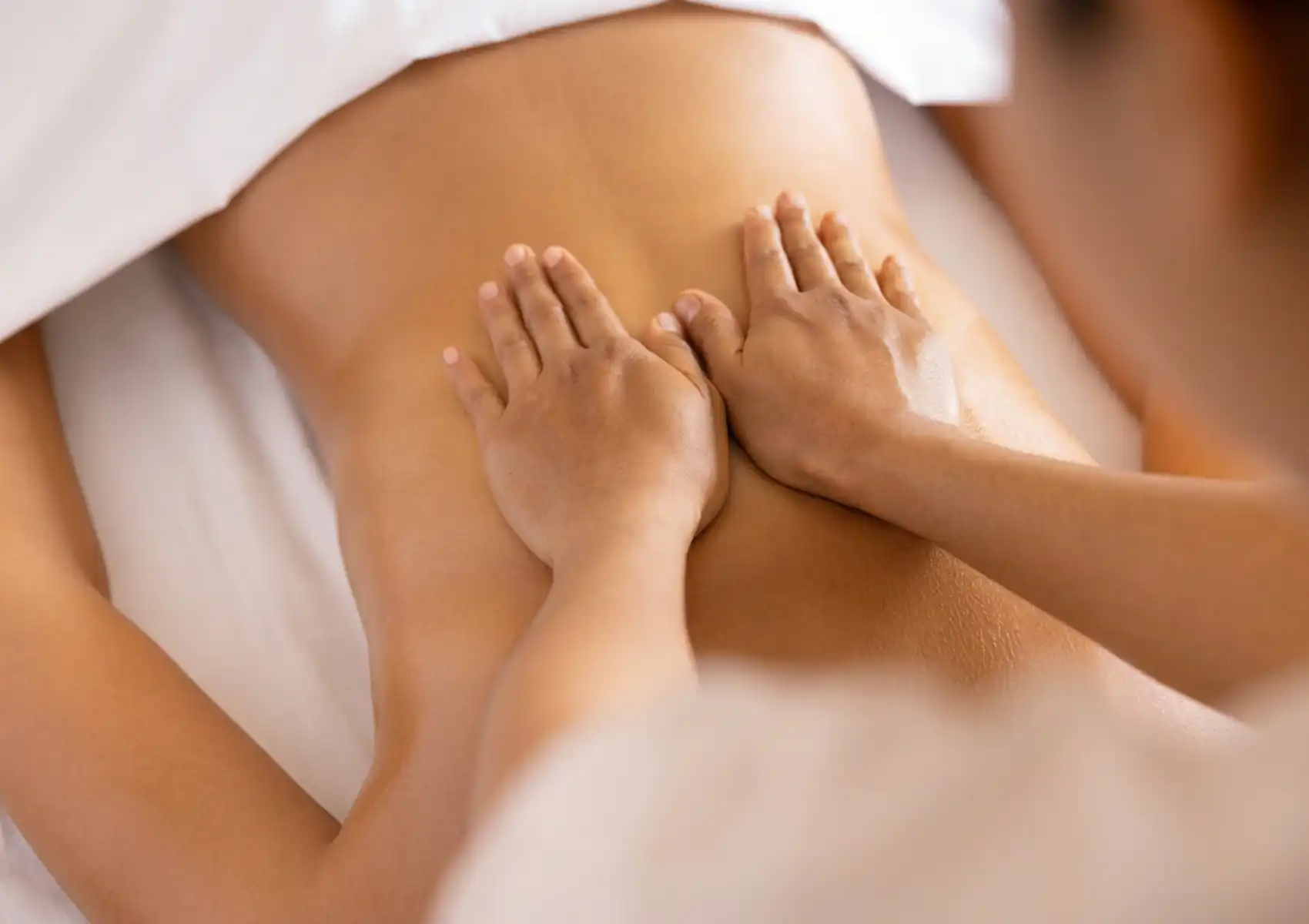 spa-retreat-ubud-bali Relaxing back massage at a Bali spa retreat, therapist’s hands gliding gently across the client’s back under soft warm lighting.