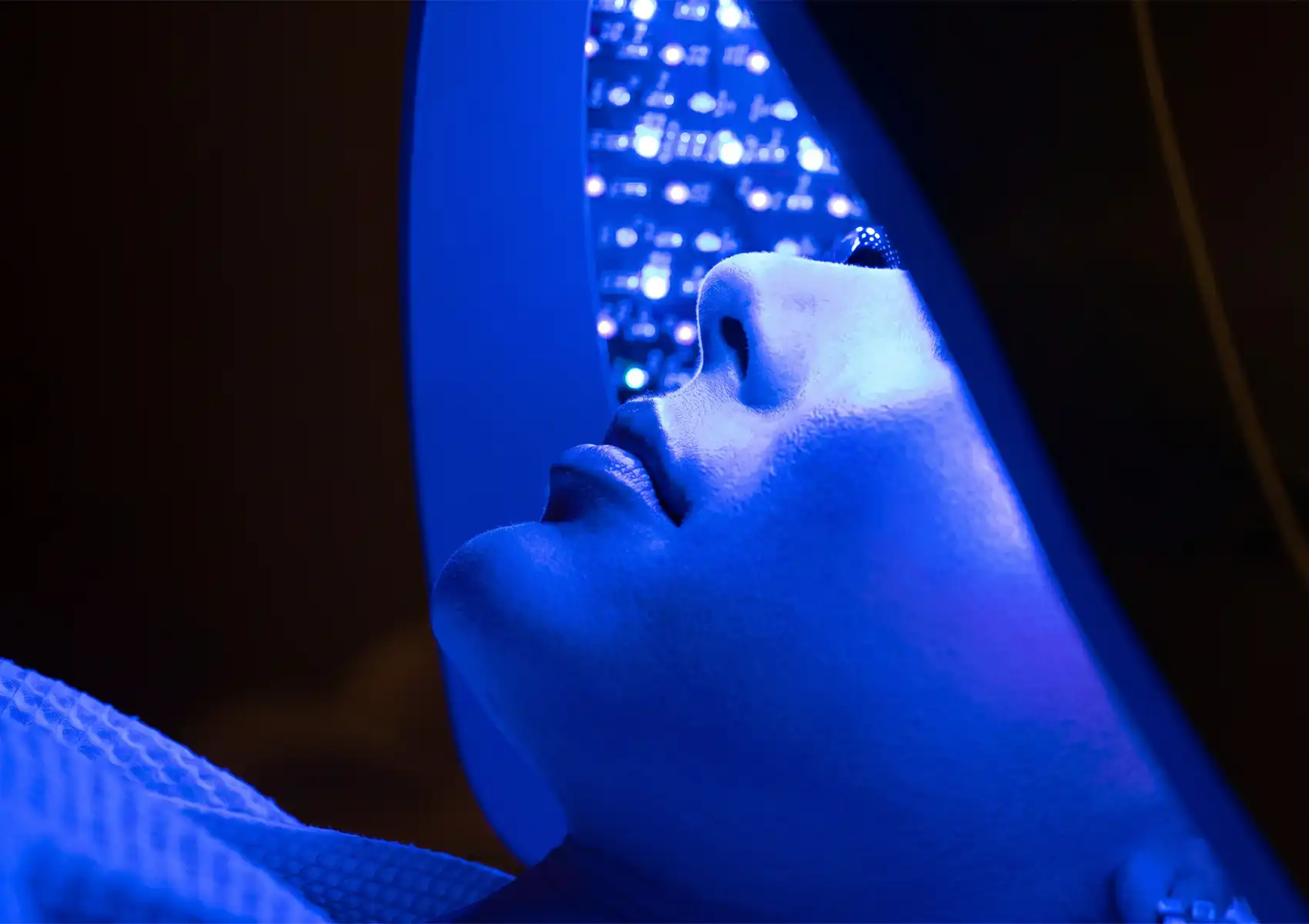 led-facial-bali Close-up profile of a client resting under a blue LED light therapy machine, highlighting the modern skincare technology utilized in advanced facial treatments Ubud.