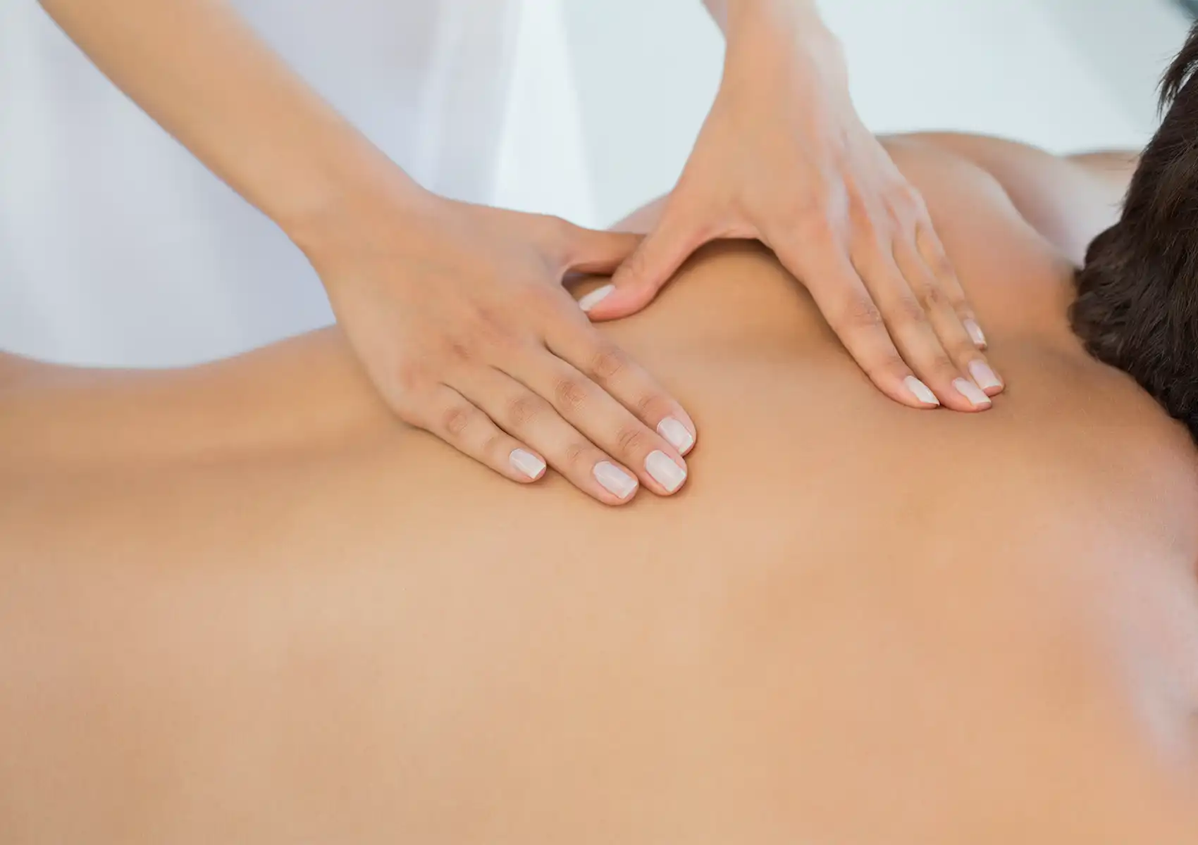 Close-up of a massage therapist's hands applying firm pressure to a client's upper back to relieve tension during a relaxing session at a spa in ubud.