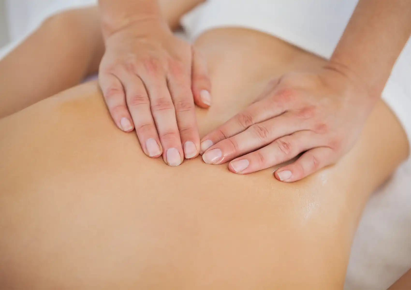 Close-up of a therapist's hands gliding with massage oil over a client's lower back during a relaxing session at a spa in ubud.