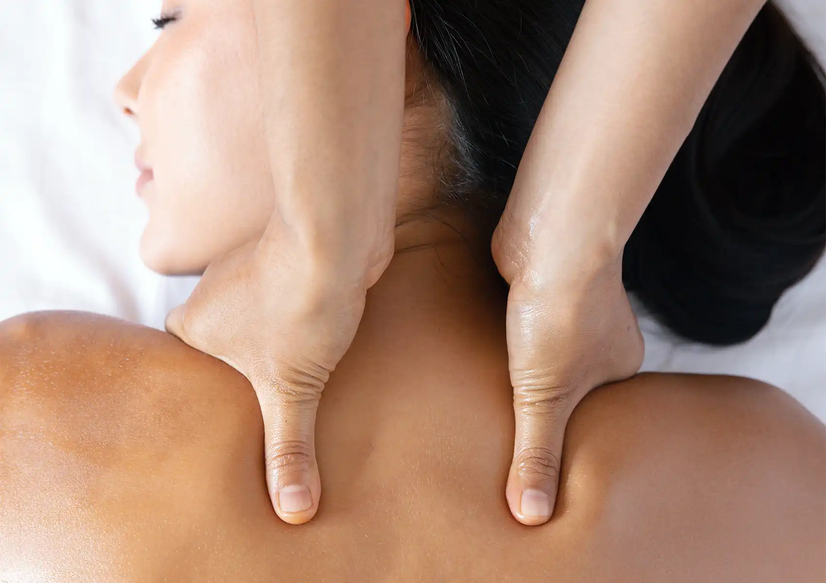 Close-up of a massage therapist applying deep thumb pressure to a client's neck and shoulders to relieve screen-induced tension during a relaxing session at a spa in ubud.