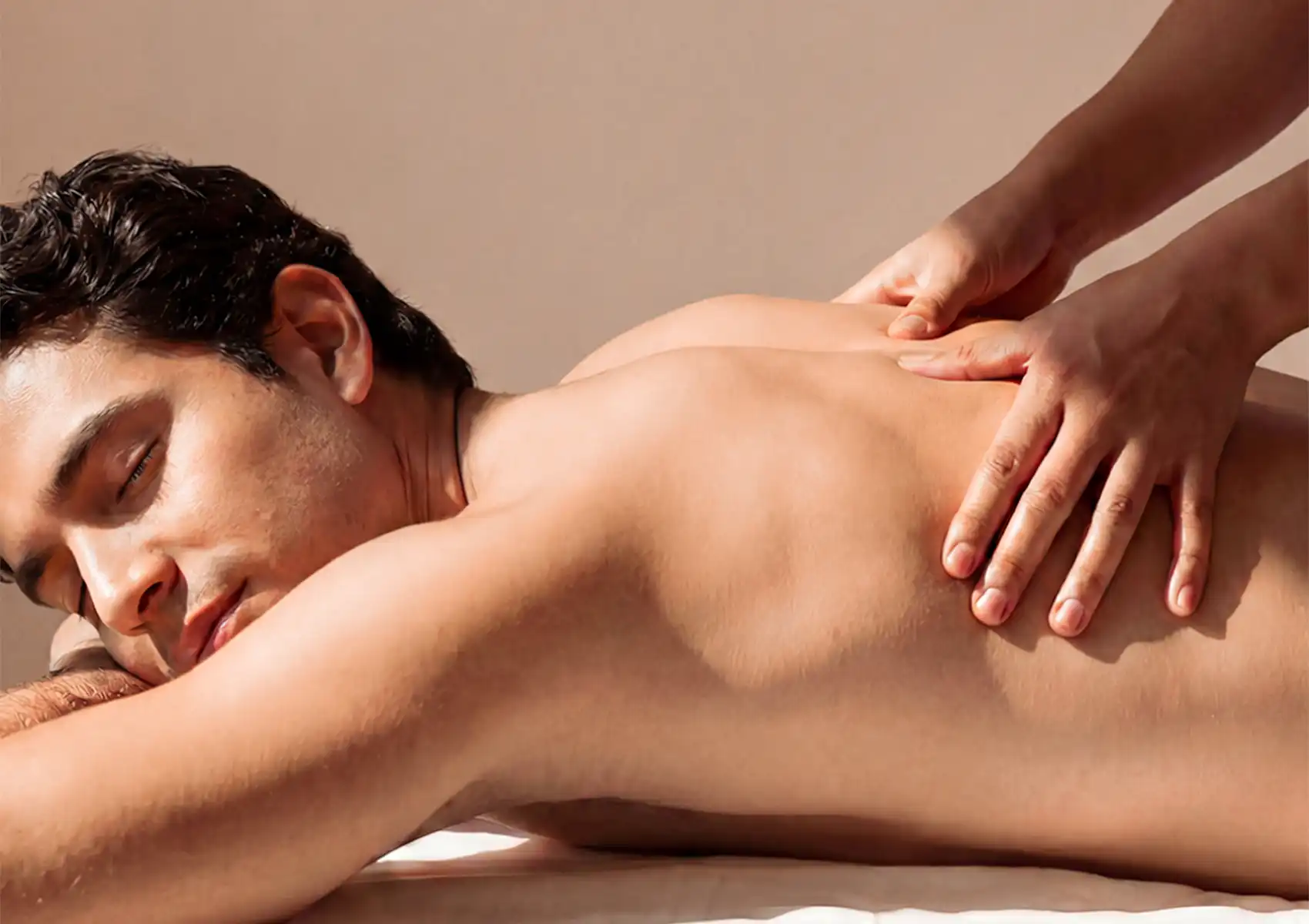 A close-up view of a relaxed man with his eyes closed receiving a soothing back massage from a therapist at a spa in Ubud.