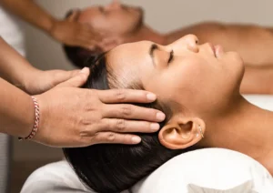 Close-up of a woman receiving a soothing head massage at the best spa in Ubud, with another guest in the background.