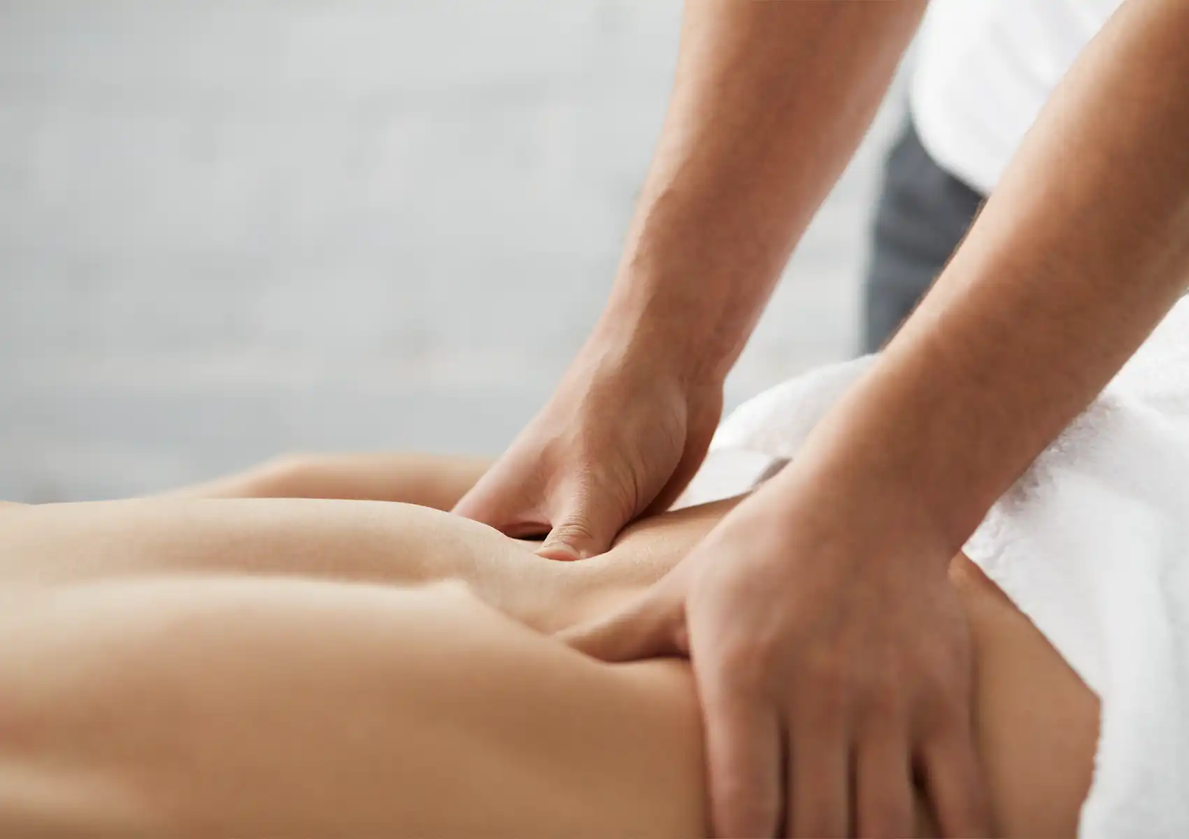 Close-up of a massage therapist's hands applying pressure to a client's lower back at the best spa in ubud.