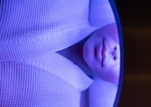 Close-up of a person in a white robe receiving a rejuvenating blue LED light therapy facial treatment at the best spa in ubud.