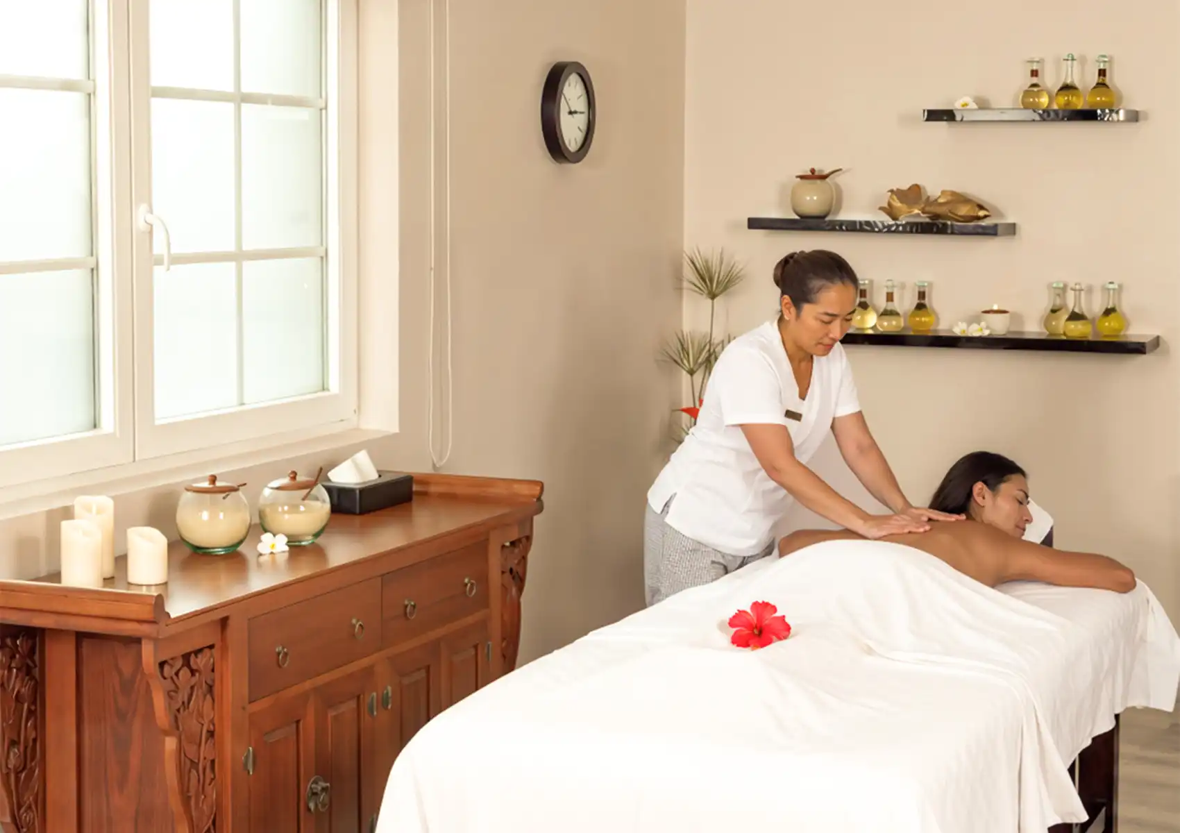 A professional therapist giving a relaxing back massage to a woman lying on a treatment table in a bright, warmly lit room at the best spa in ubud.