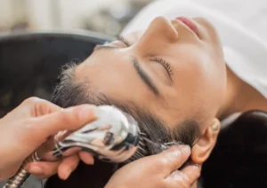 Close-up of a woman with her eyes closed relaxing while a stylist gently rinses and washes her hair at the best spa in ubud.