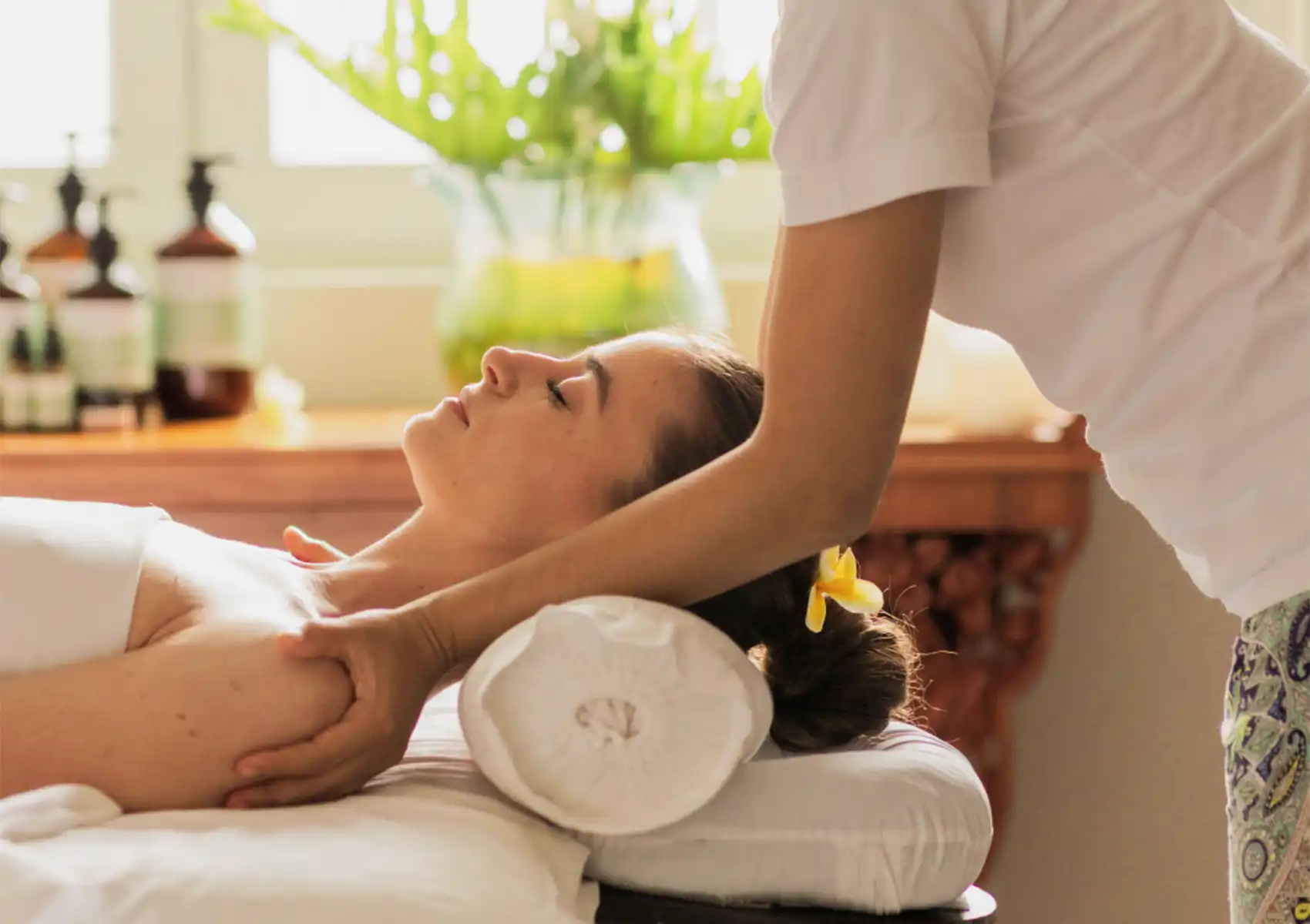 A woman receiving a calming shoulder massage from a professional therapist while resting on a comfortable treatment bed at the best spa in ubud.