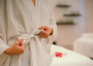 Close-up of a guest tying the belt of a white spa bathrobe, preparing for a rejuvenating treatment at the best spa in ubud.